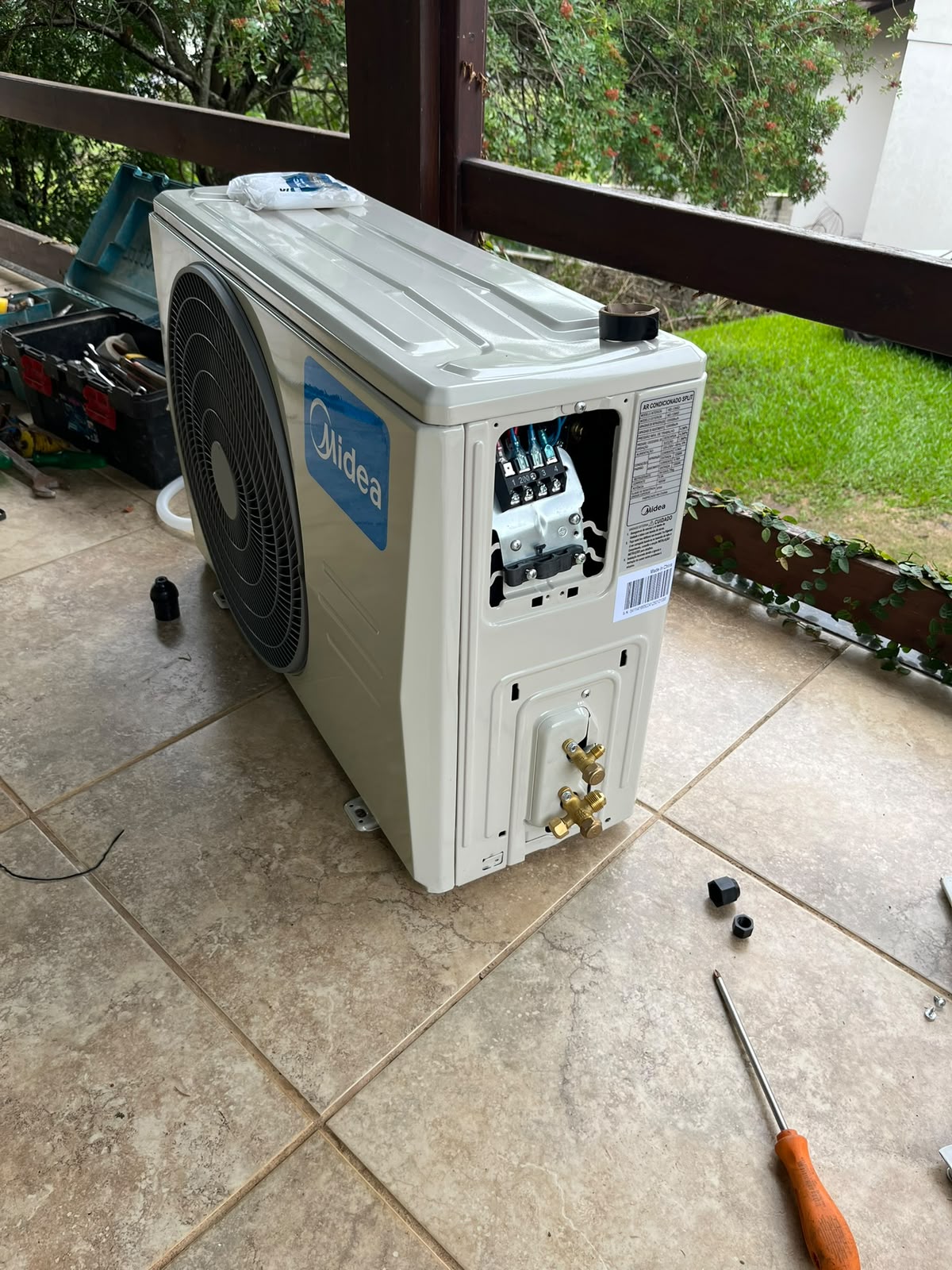 Condensadora Midea aberta durante a instalação, com as conexões elétricas à mostra